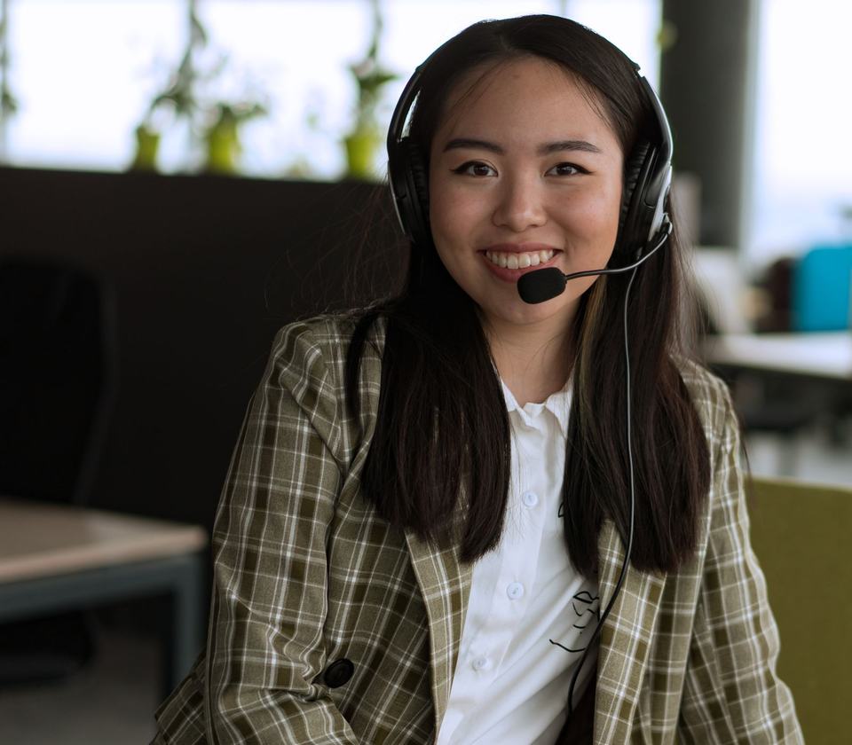 Smiling dental practice receptionist wearing a headset, answering a patient call at the front desk